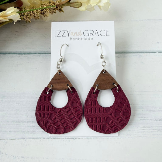 A pair of handmade teardrop dangle earrings displayed on a white card labeled 'IZZY and GRACE handmade.' The earrings have silver fishhook wires, triangular medium-brown wood tops, and textured deep burgundy lace-like lower halves.