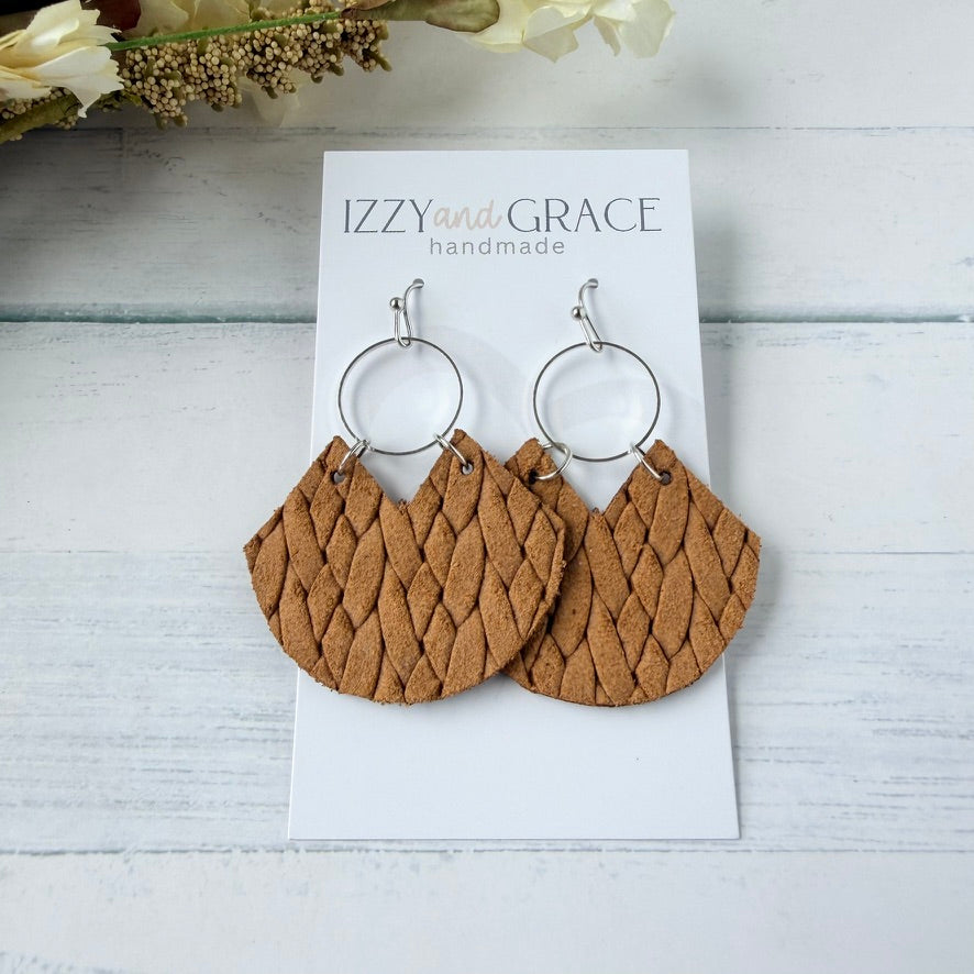 A pair of mustard woven leather dangle earrings with silver hoop backs, displayed on a white card labeled 'IZZY and GRACE handmade' on a light wood background.