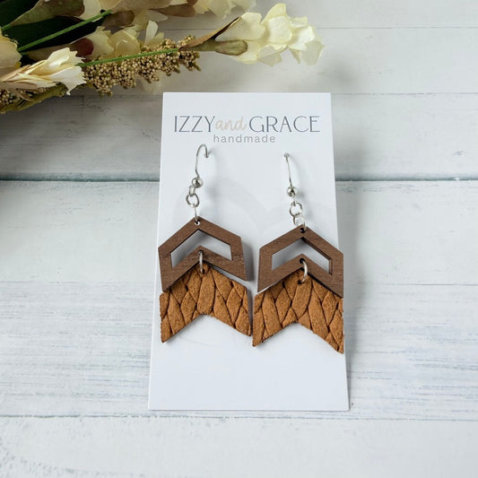 A pair of handmade geometric dangle earrings displayed on a white card. The earrings feature a dark brown chevron top and a textured mustard leather chevron bottom with a fishhook ear wire.