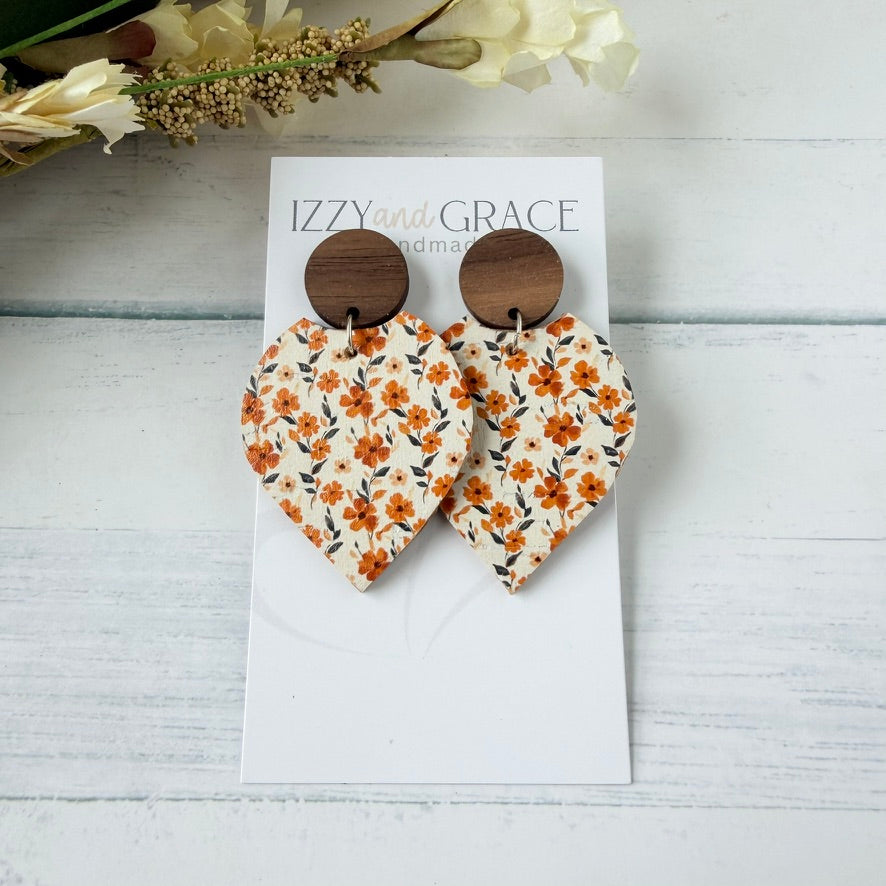 petal-shaped dangle earrings with a white leather printed with orange and flowers, featuring round wooden studs, displayed on a white card labeled 'IZZY and GRACE'.